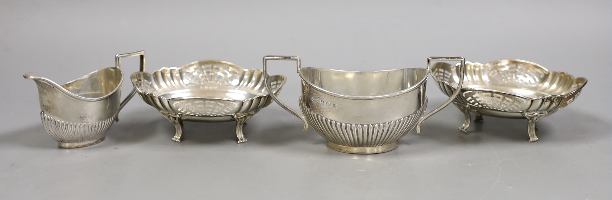 A George V demi fluted silver cream jug and sugar bowl, Birmingham, 1911 and a pair of pierced silver bonbon dishes, Birmingham, 1928, 8oz.